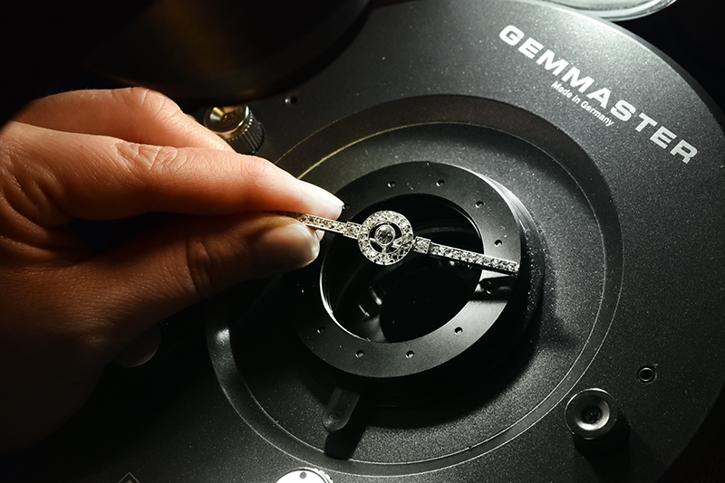 Antique diamond brooch being examined under a gemstone microscope