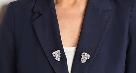 Zwei diamantbesetzte Dress Clips am Revers eines dunkelblauen Damenblazers
