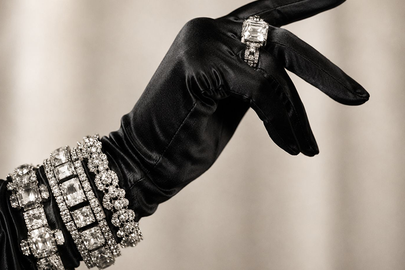 Elegante Damenhand mit schwarzem Seidenhandschuh und opulentem Diamantschmuck