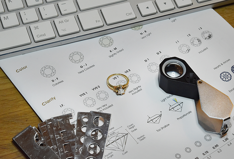 Various diamond grading tools are laid out on a workbench in front of a computer