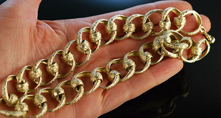 Goldene Hobelspankette auf der Handfläche einer Frau liegend