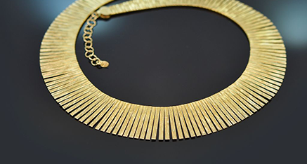 Goldene Kleopatra Kette auf schwarzem Grund liegend