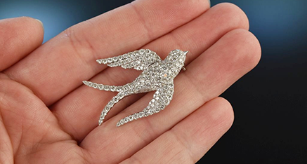 Schwalben Brosche vollständig mit zahlreichen kleinen Diamnaten ausgefasst auf einer Frauenhand ruhend