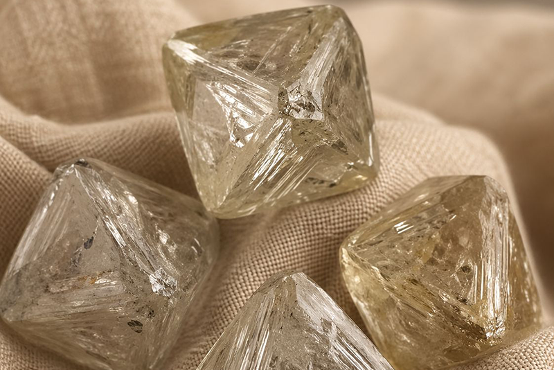 Rough diamonds in their natural octahedral form on a beige cloth