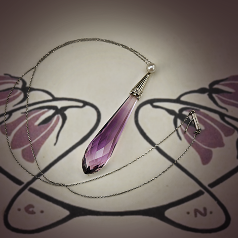 Historische Kette mit großen Amethysttropfen liegt auf typischem Jugendstilmuster in Violett.