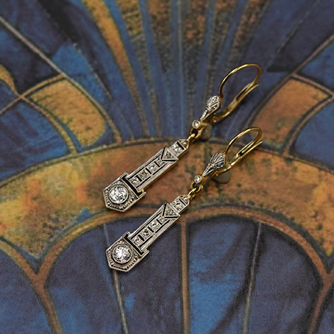 Ein Paar Art Deco Ohrringe mit Diamanten liegt auf typischen Art Deco Muster