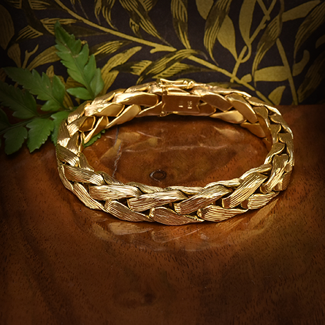 Goldenes Armbandliegt auf einem Holztisch